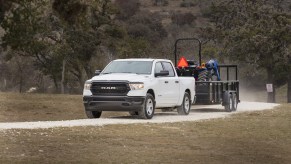 White Ram 1500 pickup truck towing a tractor.