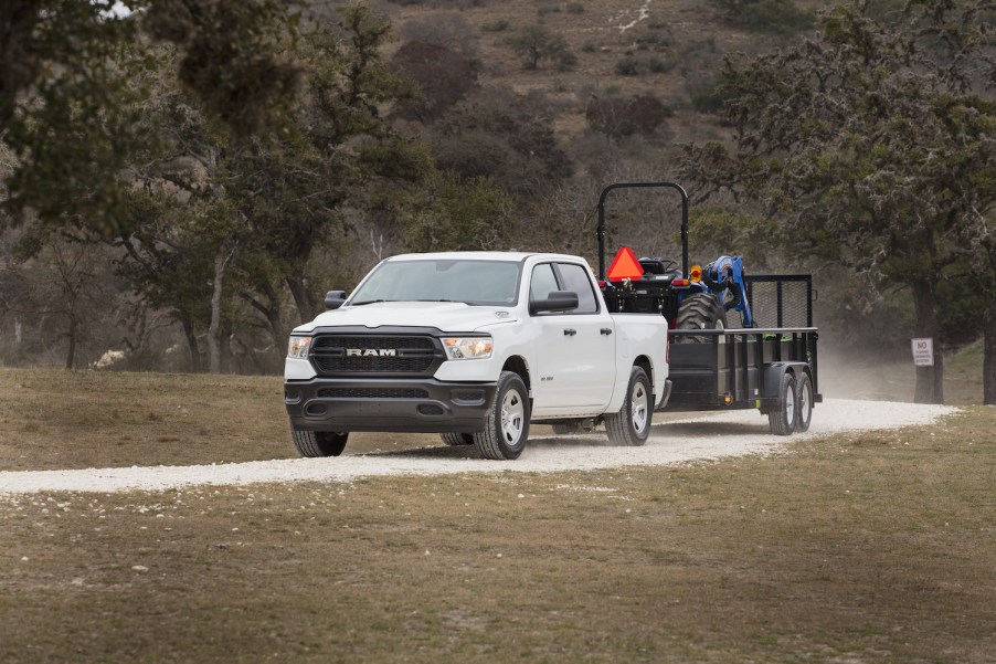 White Ram 1500 pickup truck towing a tractor.