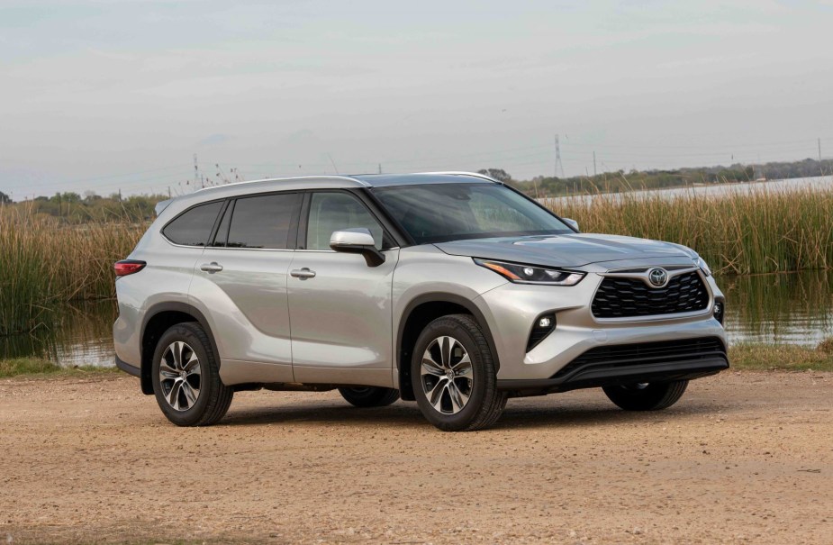 A silver gray 2022 Toyota Highlander XLE midsize SUV model parked near a marsh with water reeds