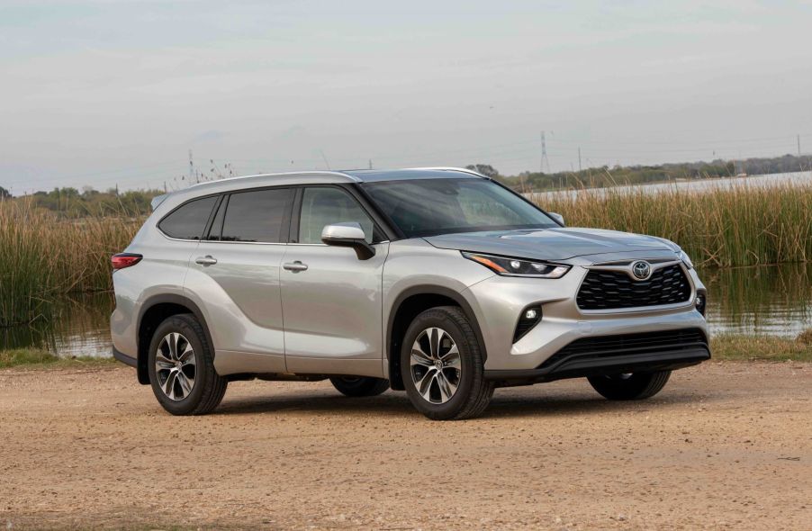 A silver gray 2022 Toyota Highlander XLE midsize SUV model parked near a marsh with water reeds