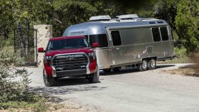 Red Toyota Tundra pickup truck demonstrating its towing capacity by pulling a camper trailer.