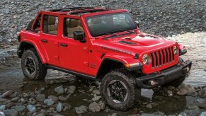 A red 2022 Jeep Wrangler splashing into a lake.