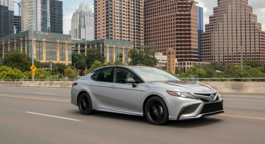 2022 Toyota Camry XSE Hybrid in silver driving down a road.