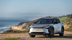 A 2023 Toyota bZ4X Limited EV/electric SUV model in Elemental Silver Metallic parked on a cliff near crashing waves