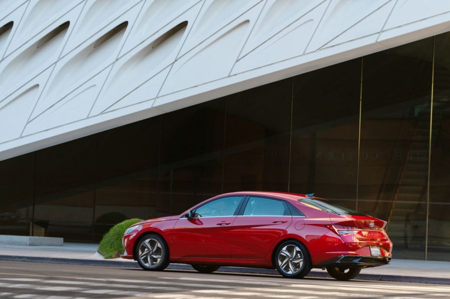 Red 2023 Hyundai Elantra midsize sedan parked in front a modern-looking building