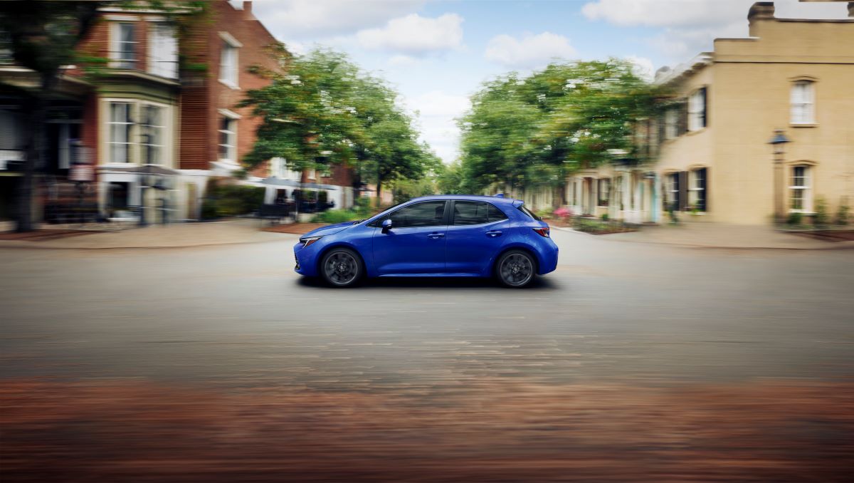 2023 Toyota Corolla Hatchback in Blue Crush Metallic driving through a city