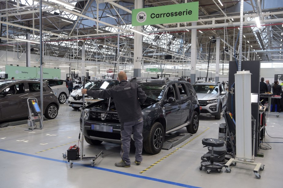 A mechanic performing an inspection on several used cars in a French factory