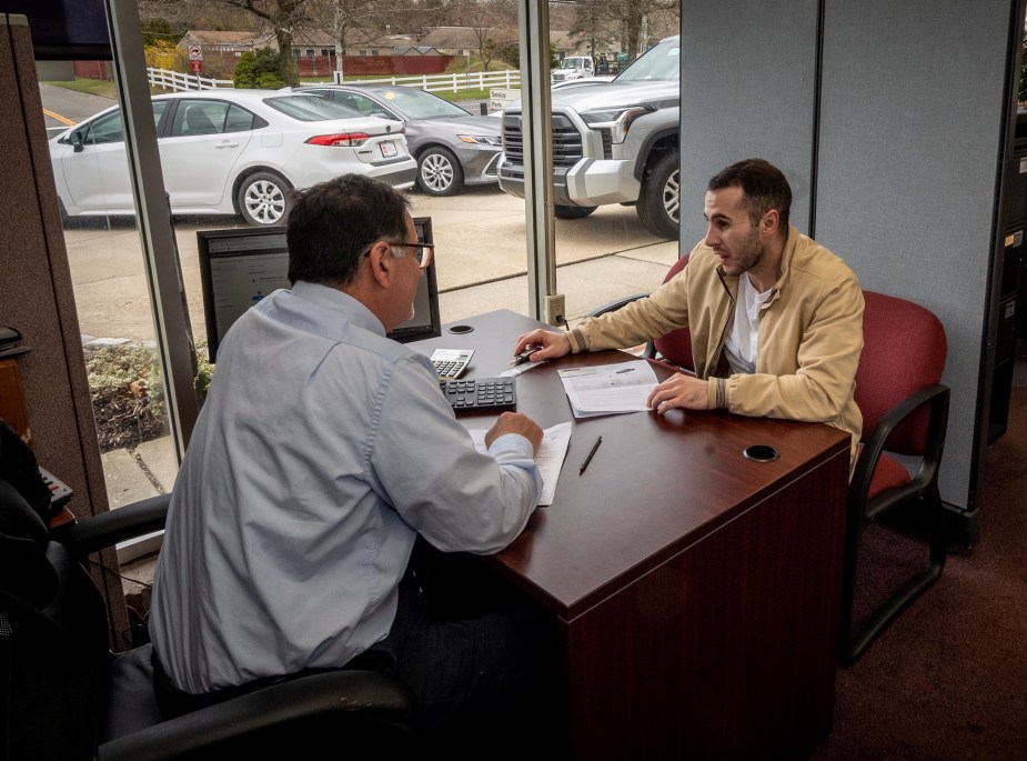 A person sitting doing a car deal, potentially car leasing. 