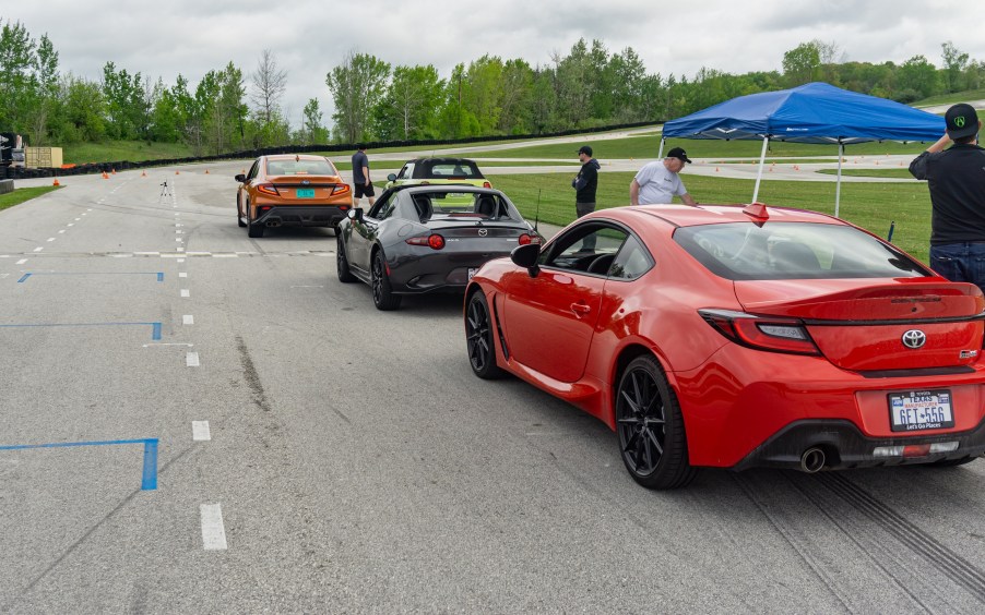 A 2022 Toyota GR86, Mazda MX-5 Miata RF, Subaru WRX, and Mini Cooper S Convertible lined up on Road America's go-kart track for autocross racing