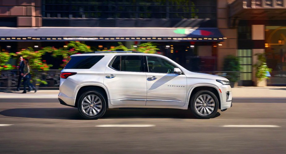 A white 2023 Chevrolet Traverse midsize SUV is driving on the road. 