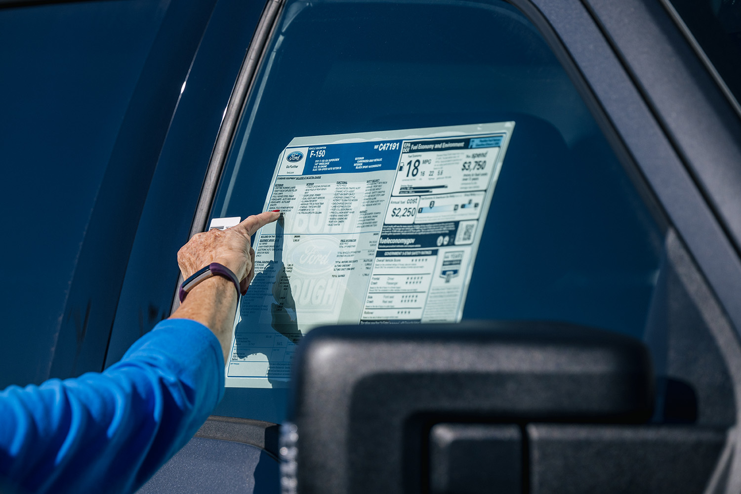 A customer inspects the Monroney sticker on a Ford vehicle at the Helfman Ford dealership