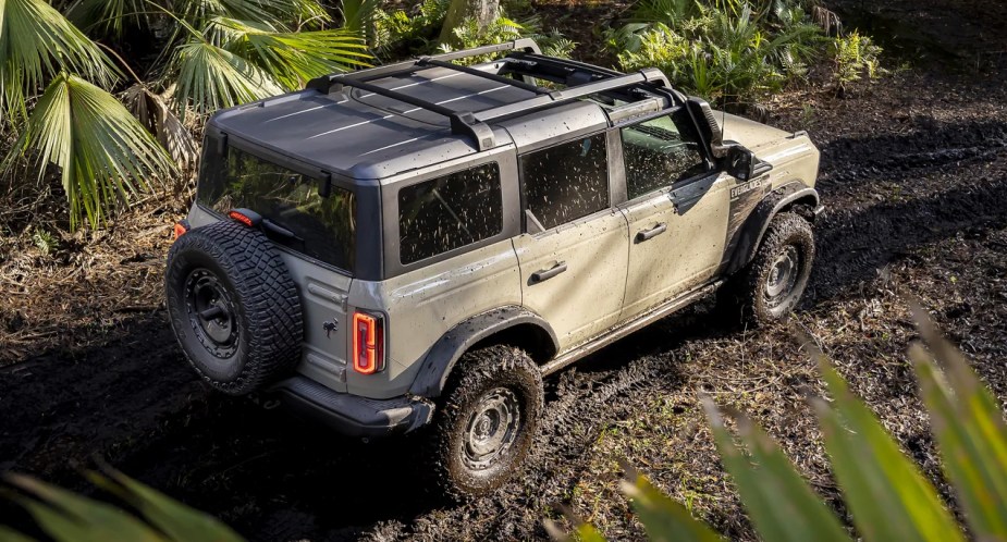 A Desert Sand color 2022 Ford Bronco small SUV is driving off-road. 