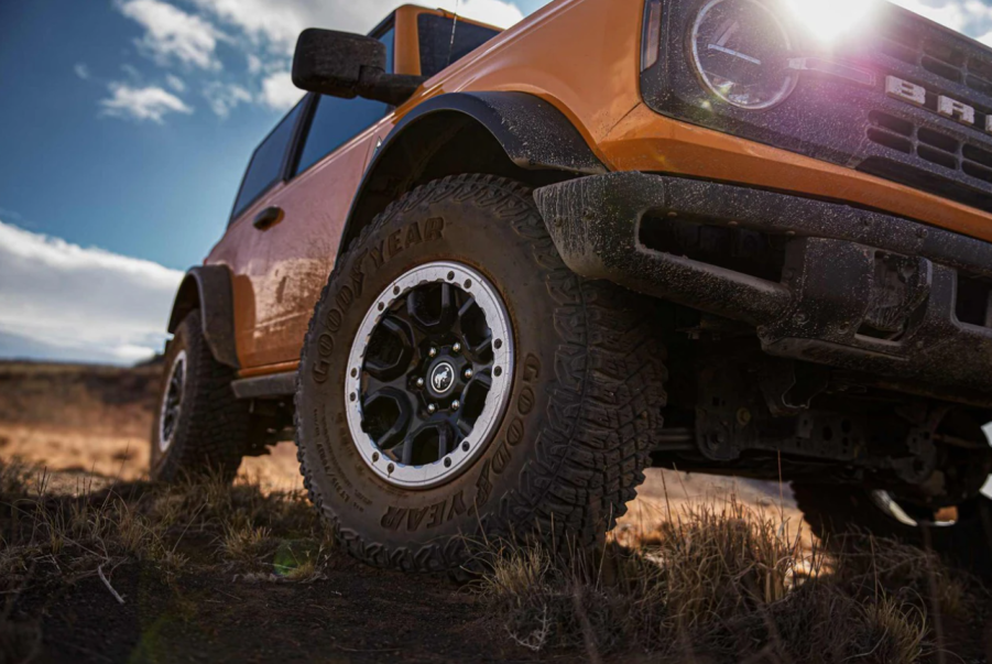 A Ford Bronco model with the Sasquatch Package parked in the wilderness with a dirty grille and tires