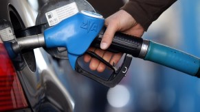 Someone pumping gas possibly deciding on buying a new car to save on gas.