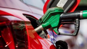 A person pumping gas, most likely experiencing high gas prices, into a red car.