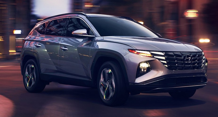 A gray 2022 Hyundai Tucson Plug-In Hybrid SUV is driving on the road. 