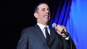 Jerry Seinfeld on a stage with blue background.