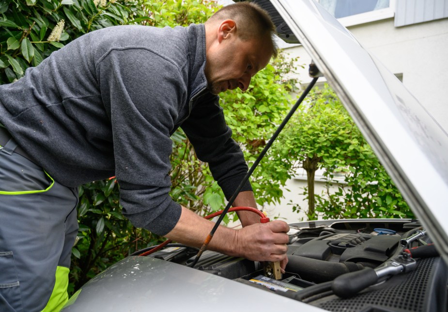 A person that hopefully will choose the best jump starter, jump starting their car.