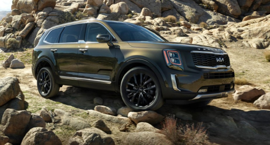 A green 2022 Kia Telluride midsize SUV is driving on rocks.