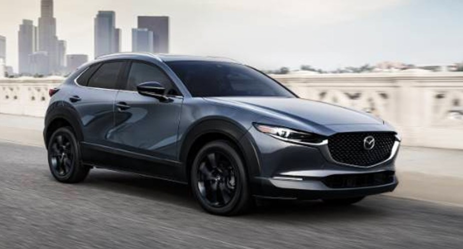 A gray 2022 Mazda CX-30 subcompact SUV is driving on the road. 