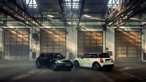 a black and white MINI Cooper in a garage area.