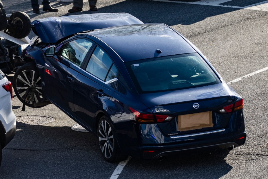 A crashed Nissan Altima gets towed away.