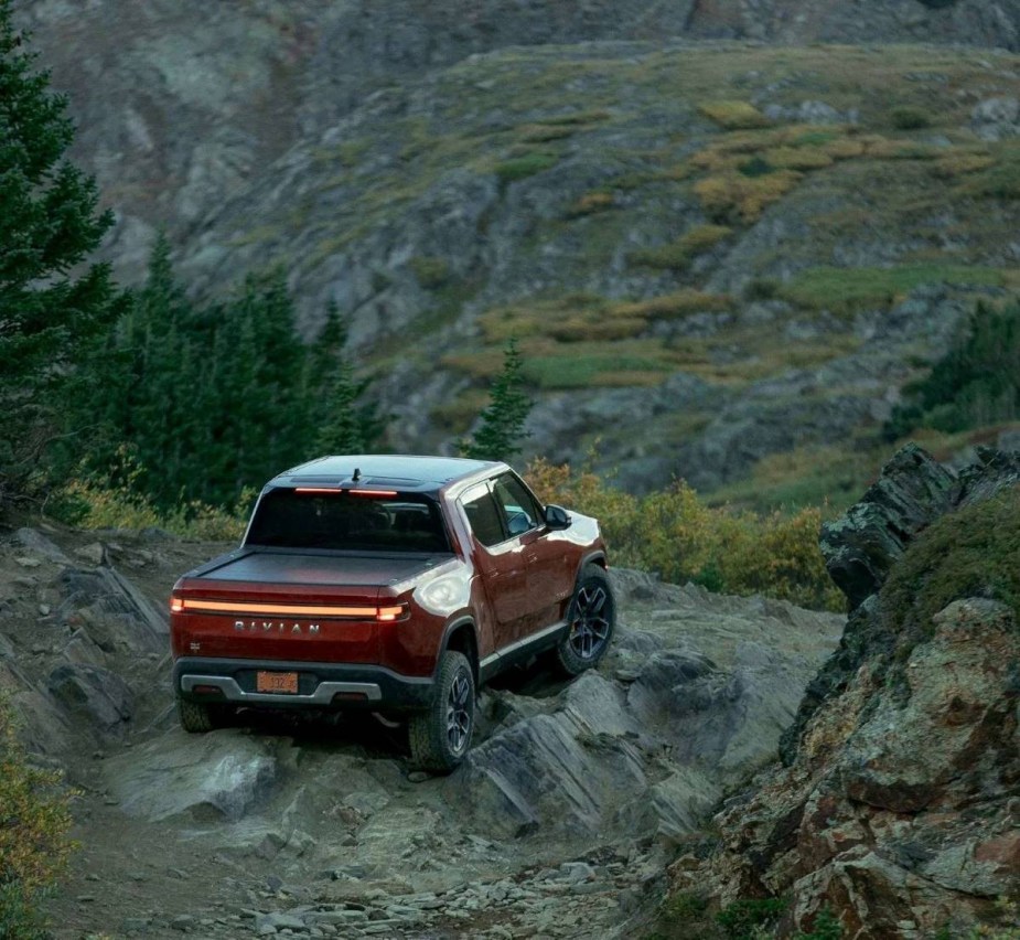 Orange Rivian R1T, a good alternative to a Tesla, parked on a rocky area