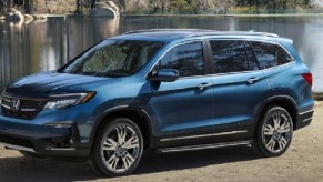 A blue 2022 Honda Pilot parked in front of a lake.