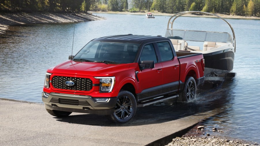 Red 2023 Ford F-150 towing a boat, highlighting its release date and price