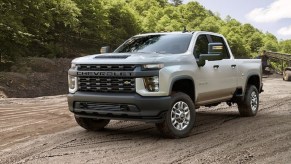 A white 2022 Chevy Silverado 2500 driving down a dirt road.