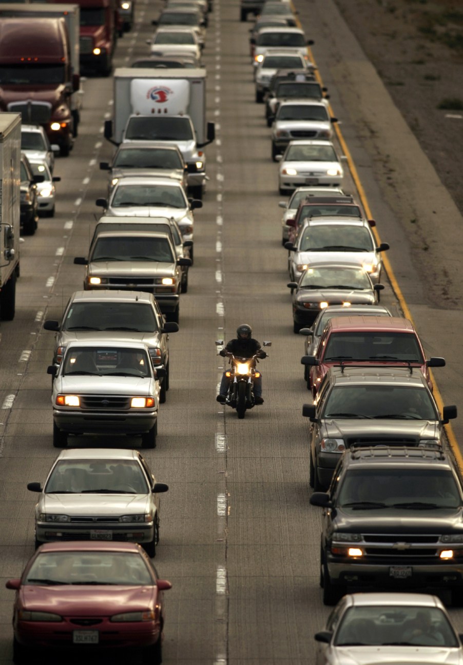 A motorcycle rider lane-spitting between cars during the commute