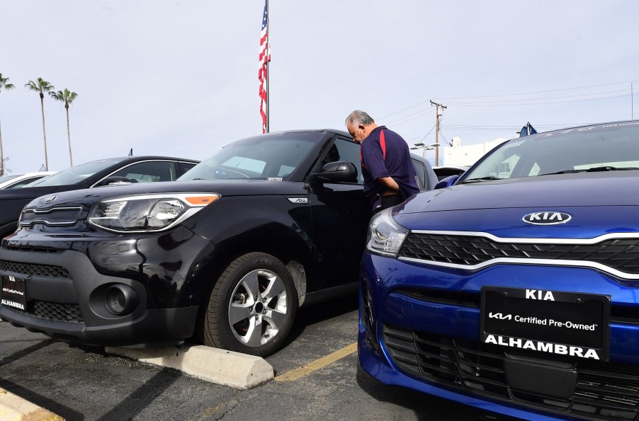 A man shopping for used cars looking at several Kias