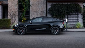 A black 2022 Tesla Model Y electric SUV is parked and charging.