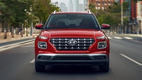 A red 2022 Hyundai Venue subcompact SUV is driving on the road.