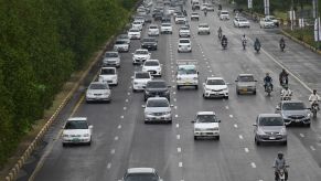 A group of cars, potentially with driver assist technology, driving down the road.