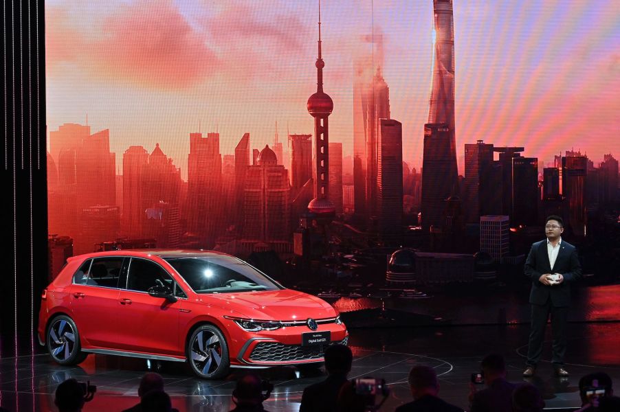 A red Volkswagen Golf GTI a sports car in front of a skyline background indoors.