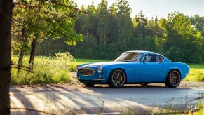 A blue Volvo P1800 Cyan parked on a forestside road