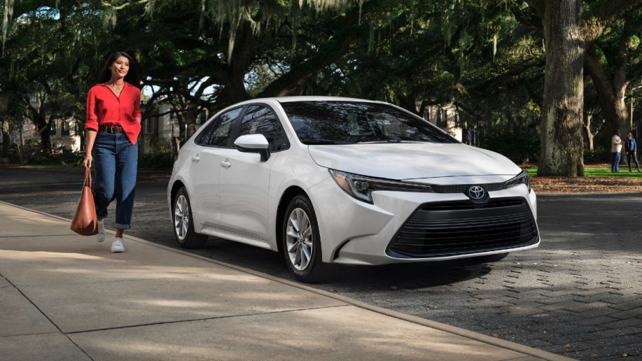 Woman walking by a Wind Chill Pearl 2023 Toyota Corolla