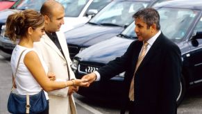 Car salesman shakes the hands of his buyers