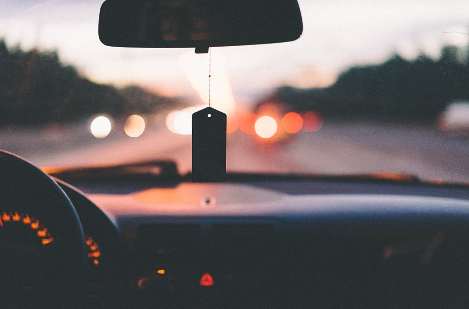 An air freshener hangs in the rearview mirror of a car.