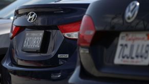 Two license plates from California on black cars.