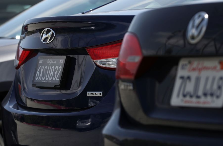 Two license plates from California on black cars.