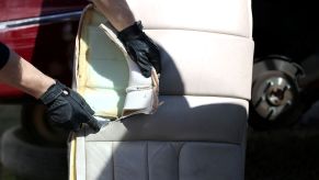 Removing old car seat leather upholstery during a reupholster process on a salvaged luxury car