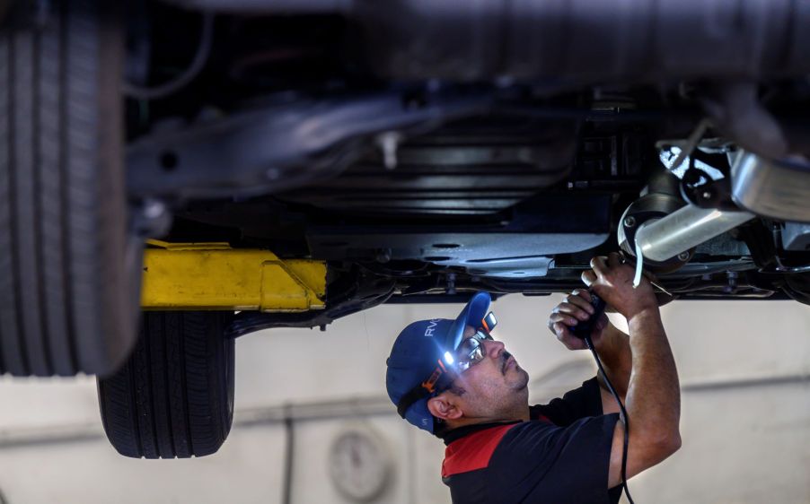 A technician marking a catalytic converter with license plate numbers to prevent theft in Huntington Beach, California