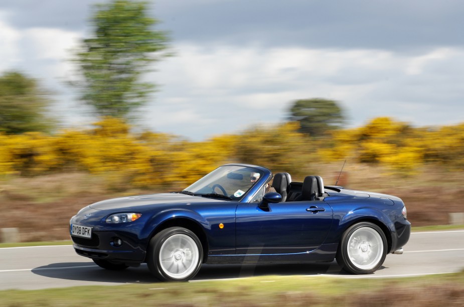 A blue 2010 Mazda MX-5 Miata sports car being driven fast