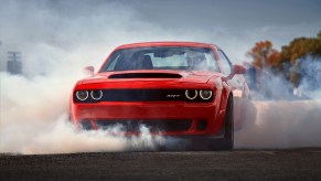 A red 2018 Dodge Challenger SRT Demon doing a burnout on a dragstrip