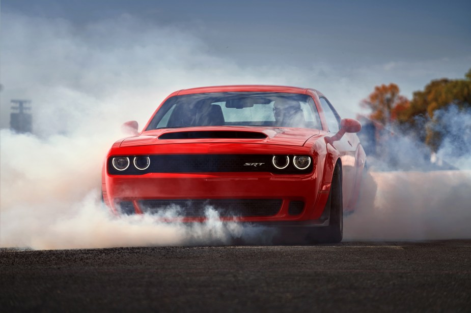 A red 2018 Dodge Challenger SRT Demon doing a burnout on a dragstrip