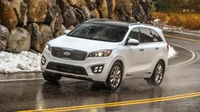 A 2018 Kia Sorento midsize SUV in white, driving on an empty road