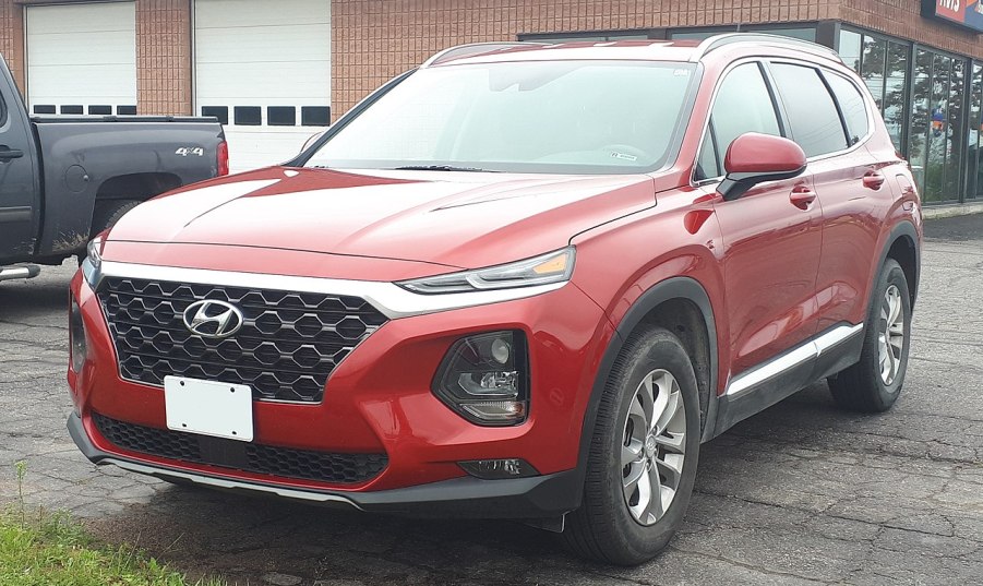 A red 2019 Hyundai Santa Fe sits parked in the street. Should you buy it used?