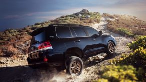 The back of a black 2021 Toyota Land Cruiser driving over a mountainous terrain.